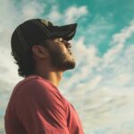 A man enjoys outdoor relaxation and mindfulness beneath a bright, cloudy sky, exuding calm and peace.